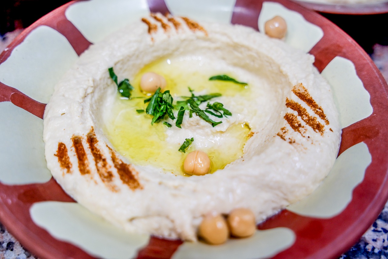 Hummus crémeux nappé d’huile d’olive, pois chiches et persil, servi dans un bol libanais