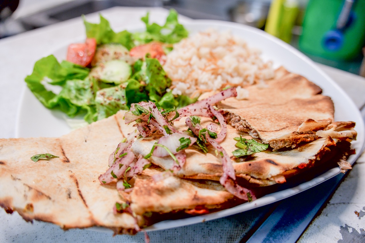 Galette de pain grillée garnie de kebbé, oignons au sumac, riz et salade