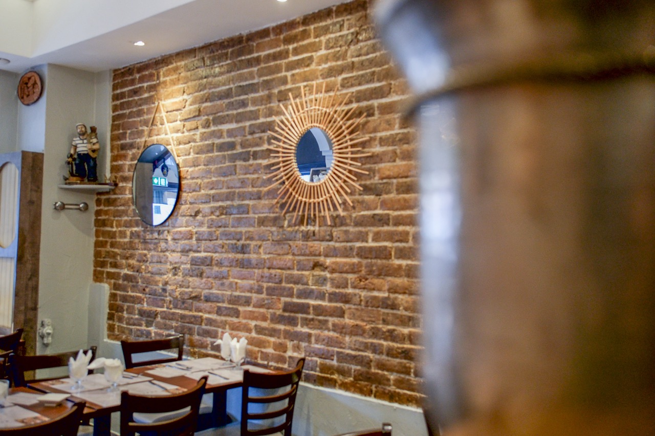 Mur de briques apparentes du restaurant Baladna avec miroirs ronds et tables en bois